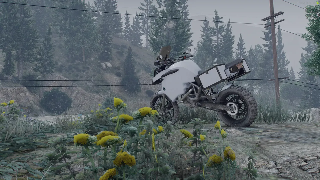 Ubermacht 1130 TTS in white with an aluminum top box, side profile on a misty hillside with yellow flowers