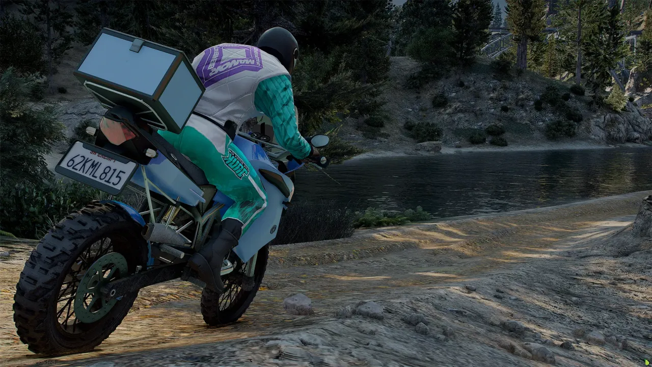 Ubermacht 1130 TTS rear view with top box and a rider in a teal suit on a dirt trail beside a lake