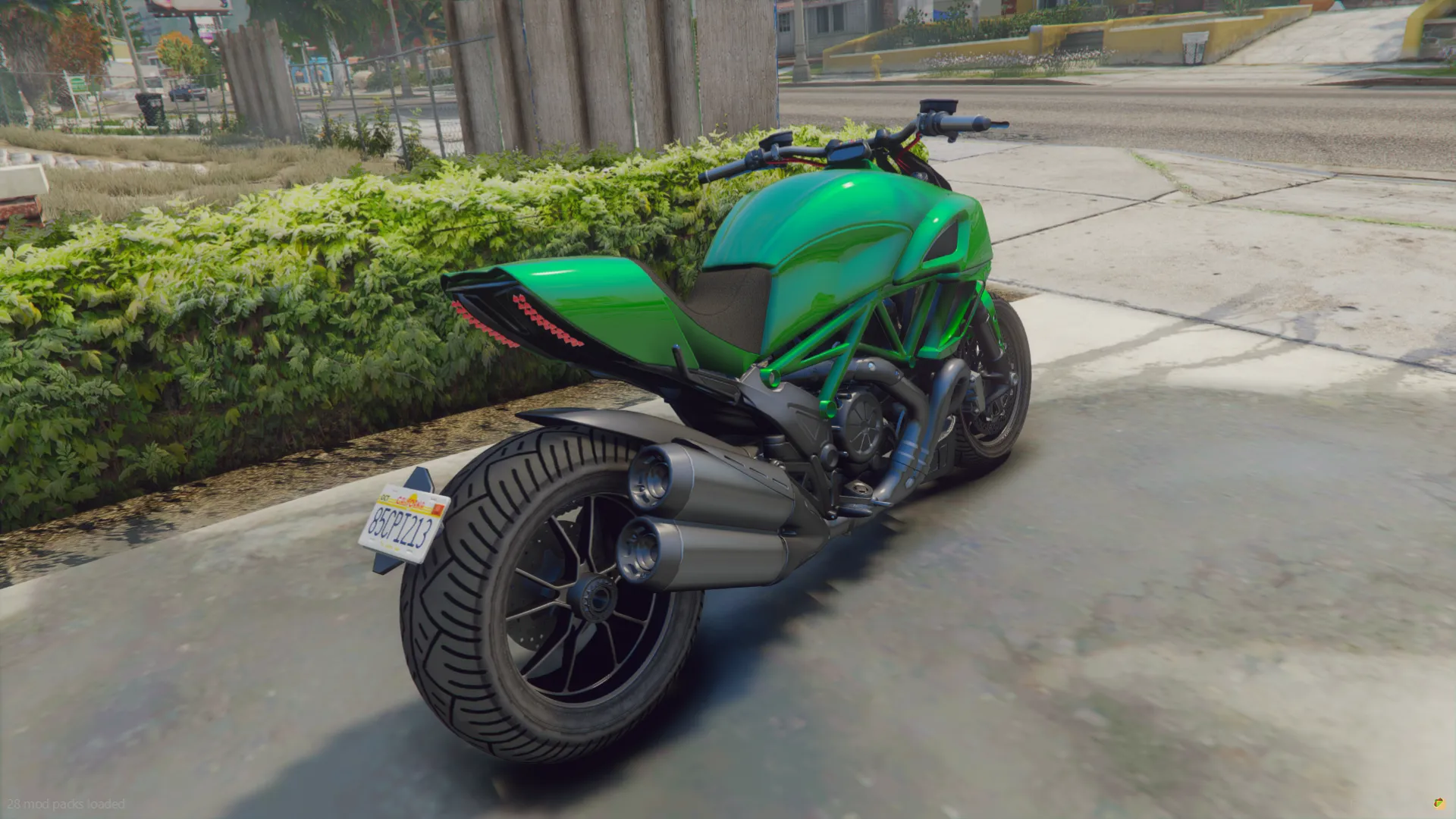 Ducati Diavel 2019 rear three-quarter view showing twin exhausts and wide rear tire, parked by a hedge
