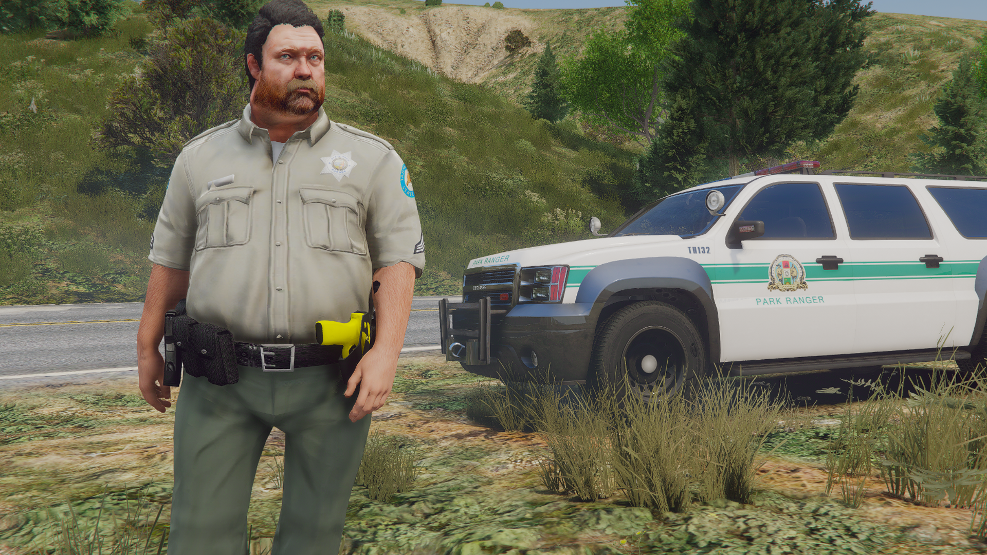 Rooster Craw in a park ranger uniform with duty belt standing beside a Park Ranger SUV