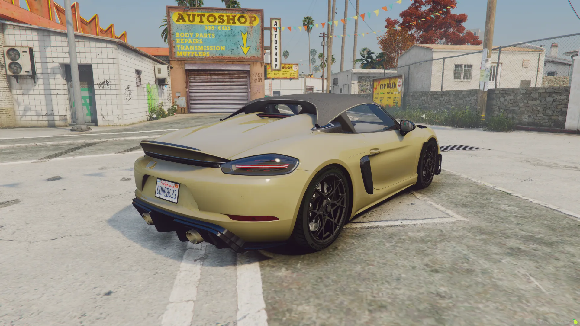 Porsche 718 Spyder RS 2024 rear three-quarter view in gold with black top near an autoshop