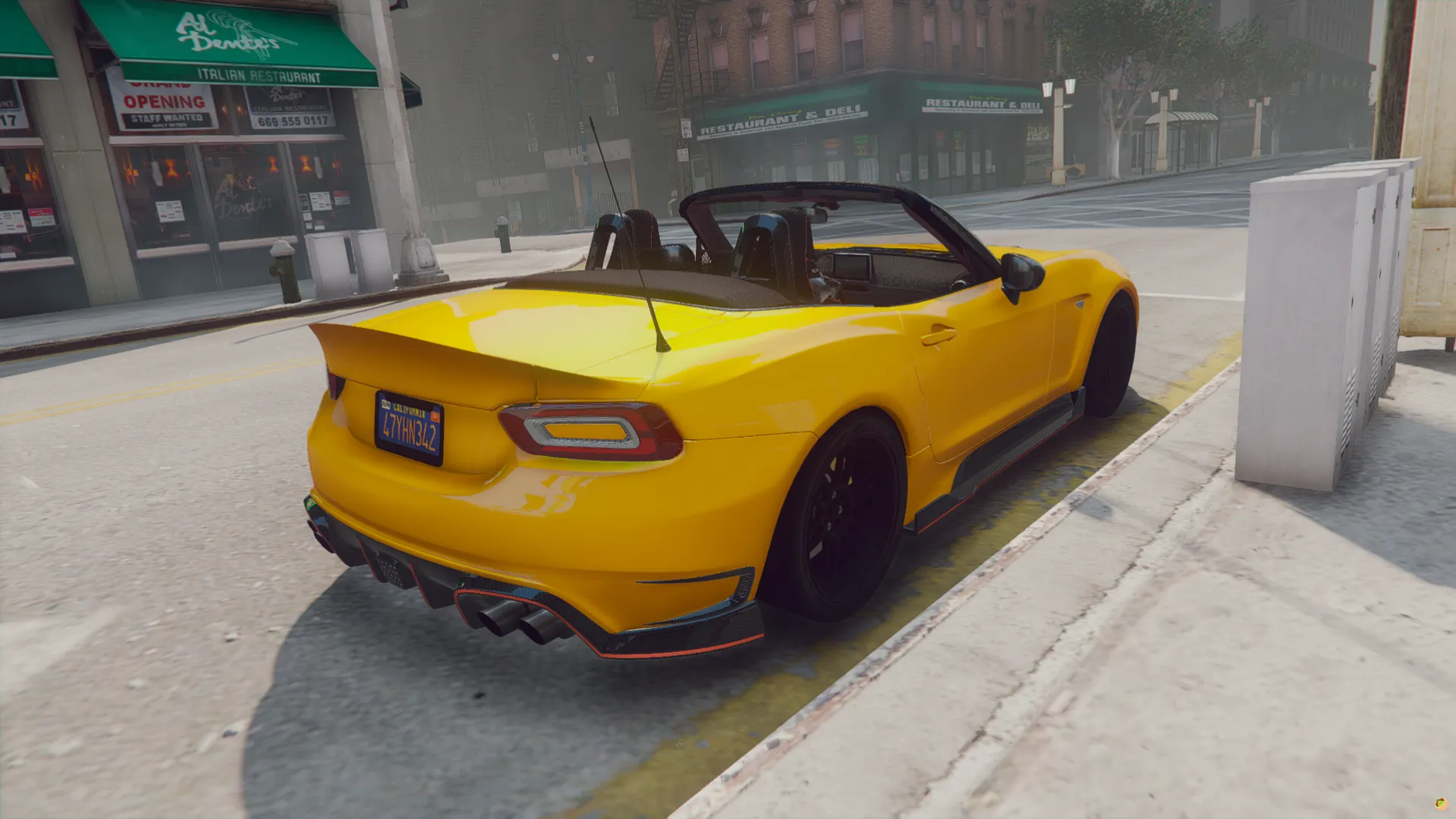 Fiat 124 Spider 2017 rear three-quarter view with the top down and a ducktail spoiler beside a shopfront