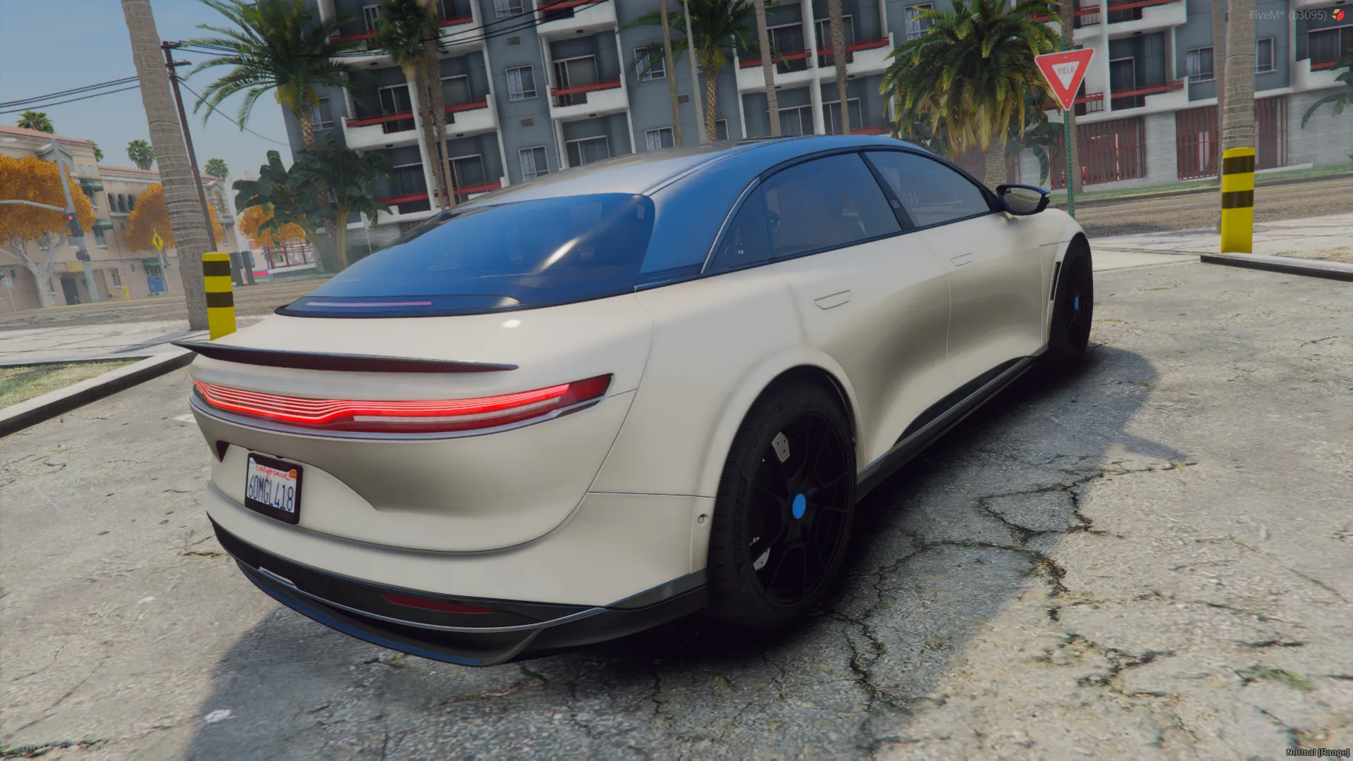Lucid Air 2024 rear three-quarter view with the full-width red taillight strip on a palm-lined city street