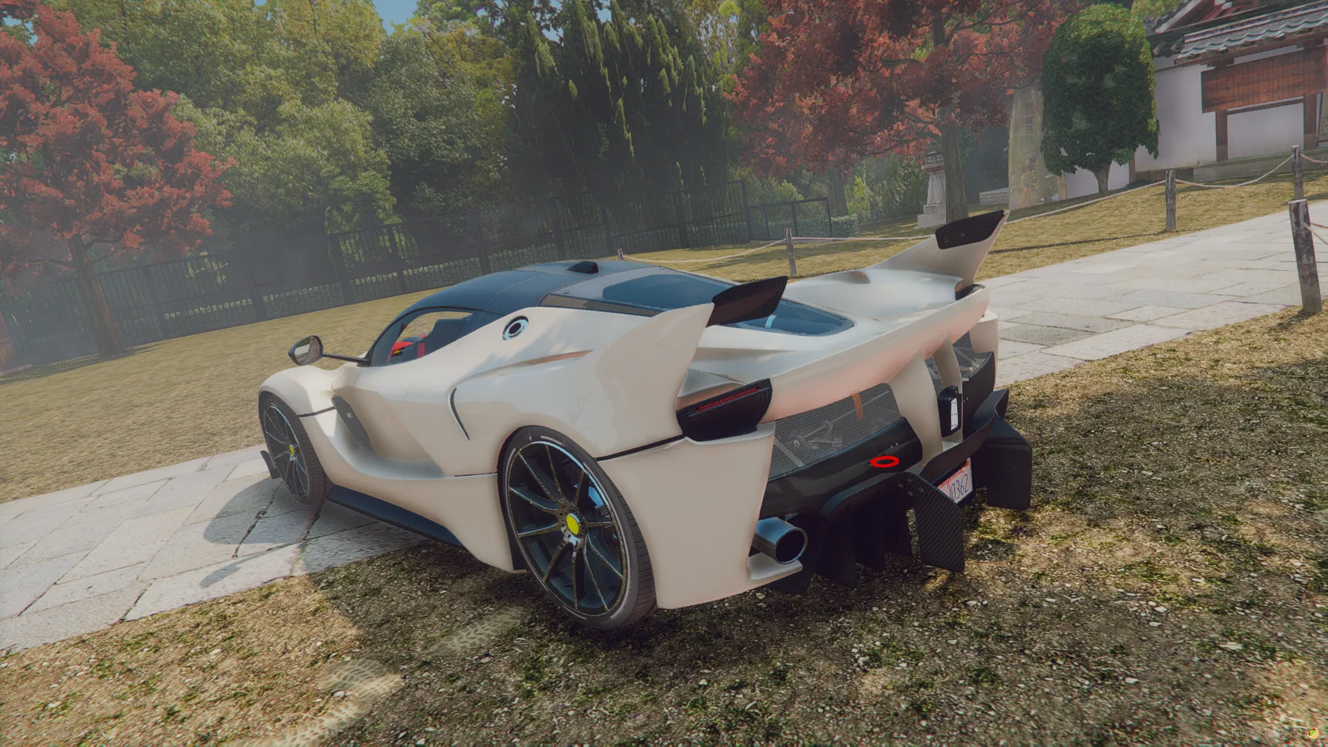 Ferrari FXX K 2015 rear three-quarter view in white with rear fins and yellow-accented wheels on grass