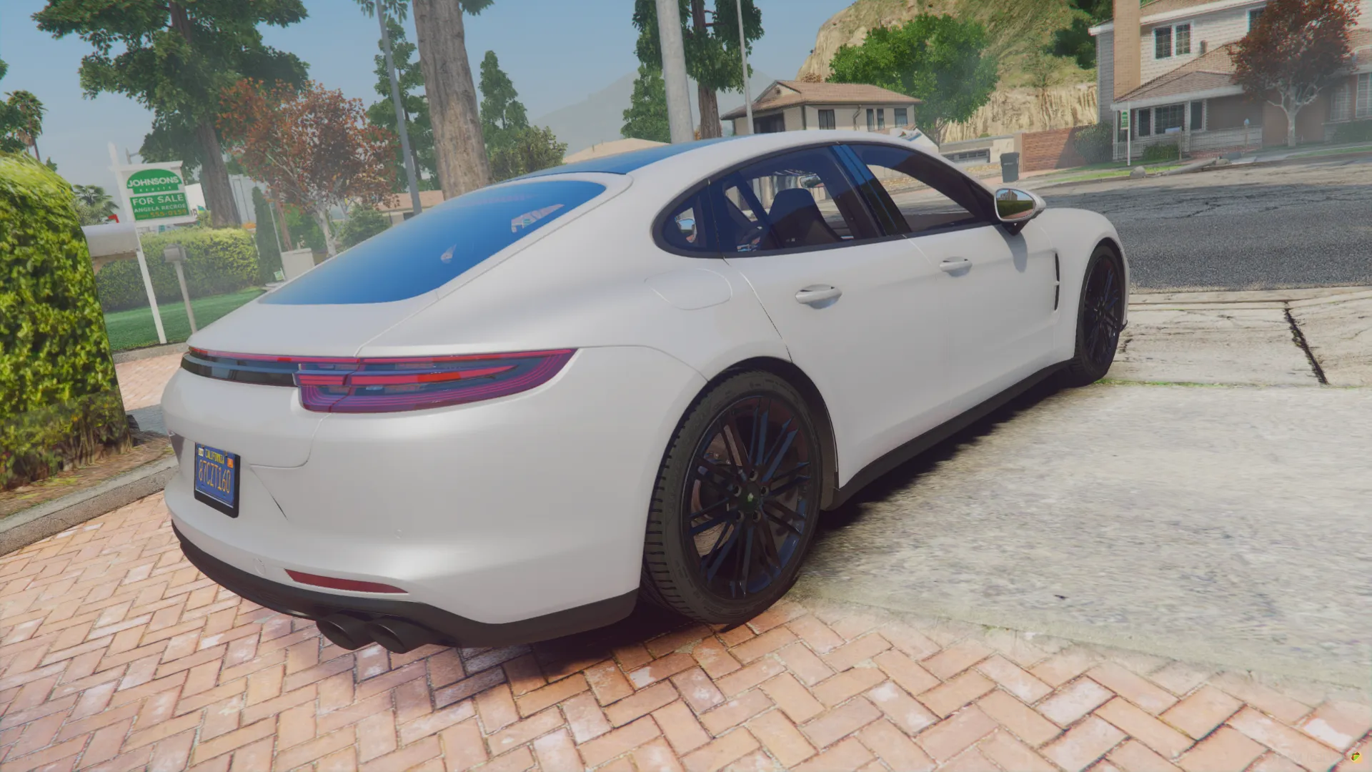 Porsche Panamera Turbo 2017 rear three-quarter view with slim taillights on a brick driveway near trees