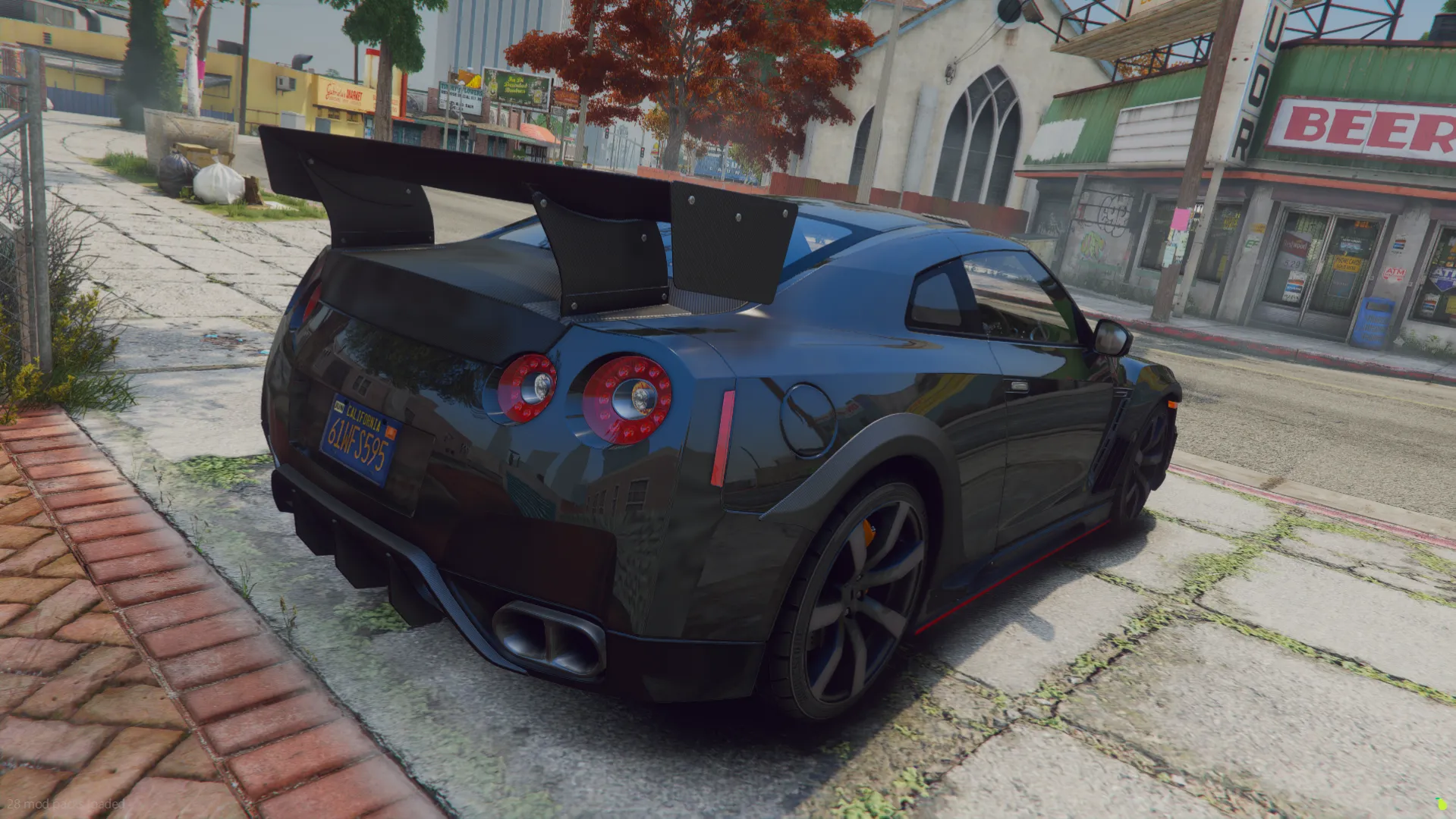 Nissan GT-R R35 rear three-quarter view in dark grey with tall rear wing and quad exhaust on a sidewalk