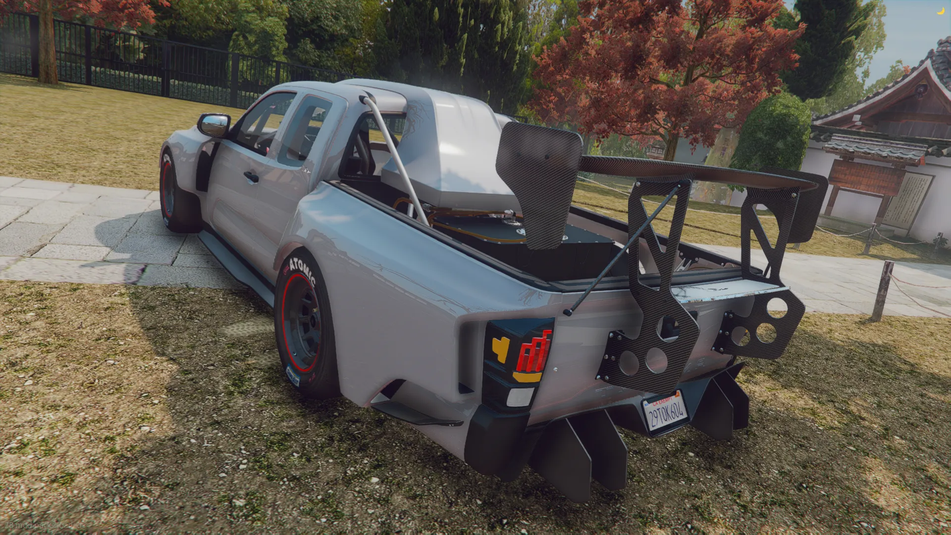 2019 DeBerti Toyota Tacoma TRD rear three-quarter view with a towering rear wing and diffuser on a park lawn